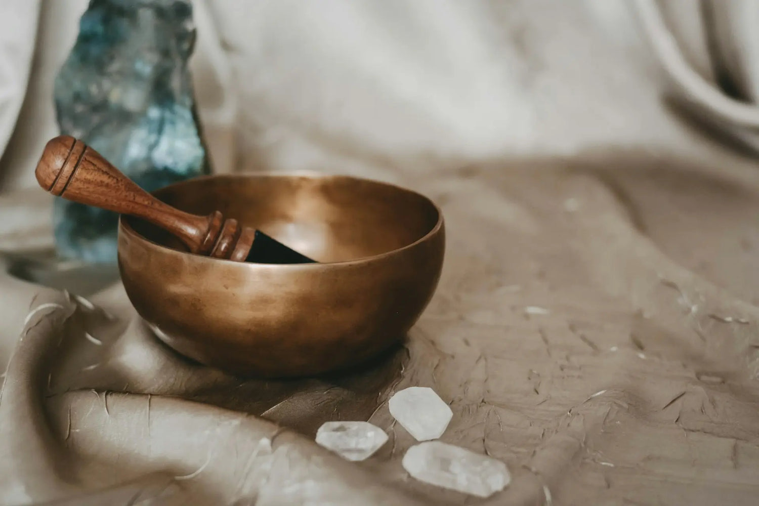 Bronze bowl with wooden handle on a textured surface