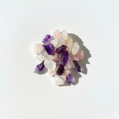 Collection of amethyst, clear quartz and rose quartz crystals on a white background