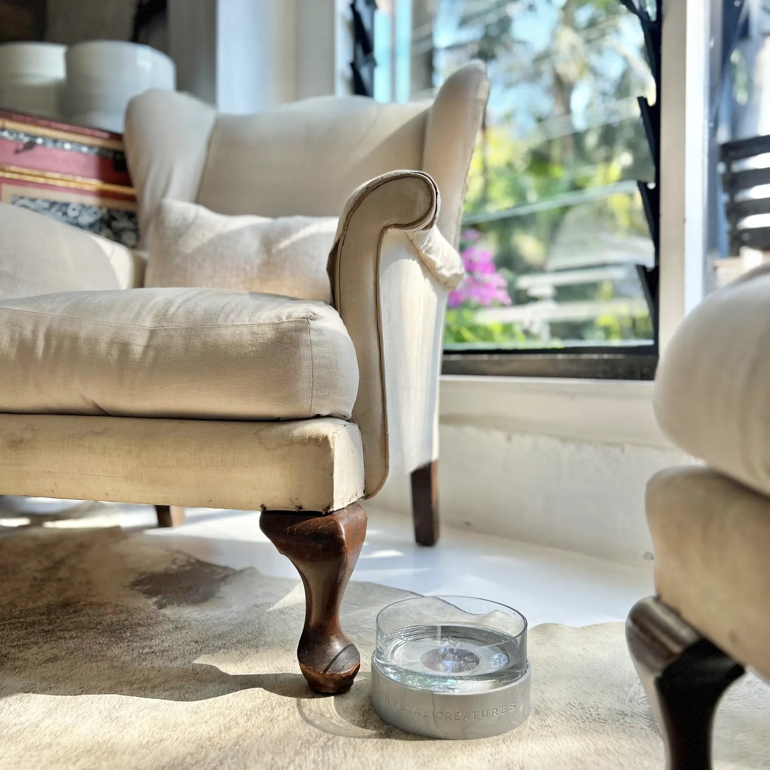 Beige armchair with wooden legs in a room with large windows and Crystal Elixir Pet Water Bowl