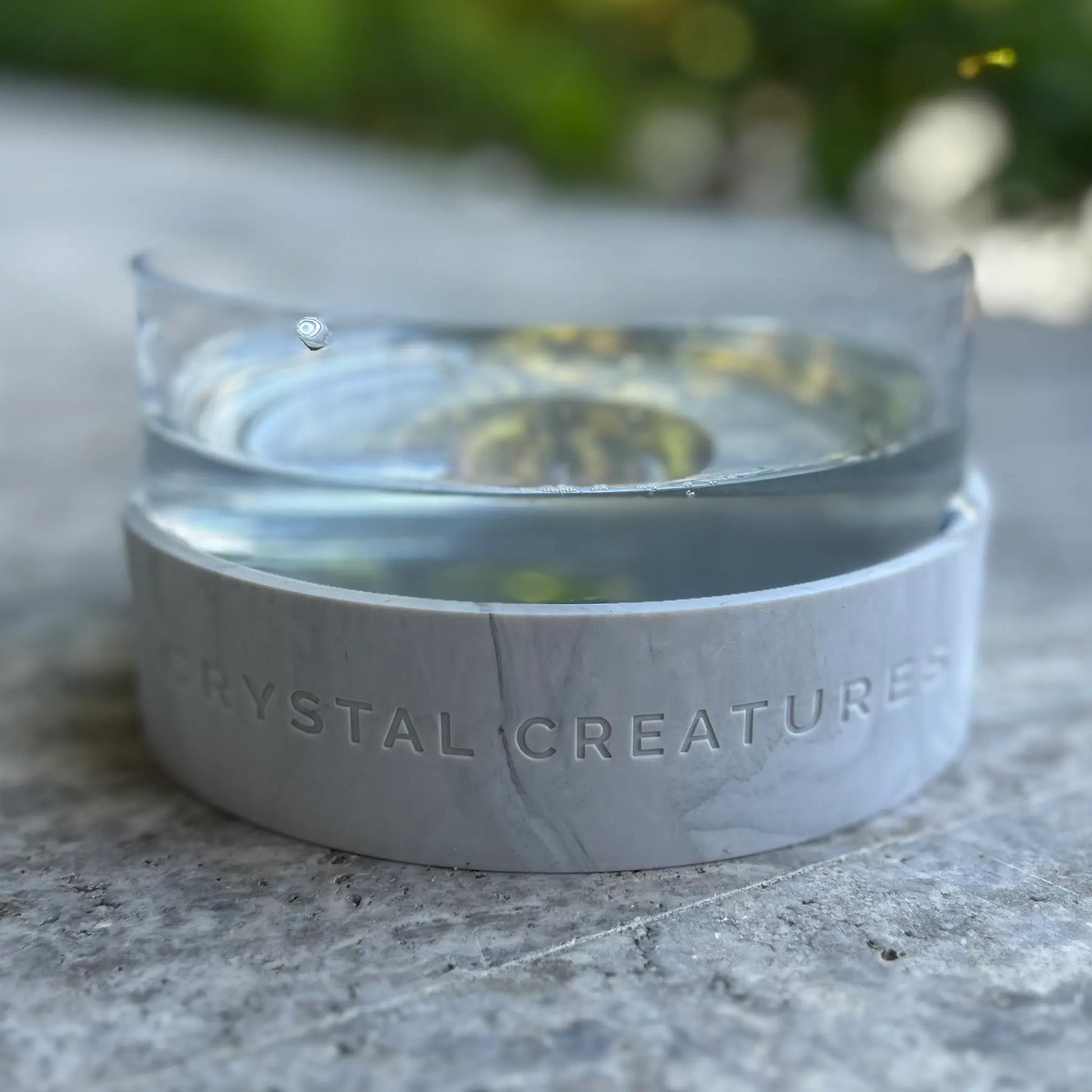 Crystal Elixir Pet Water Bowl on a stone surface with a blurred natural background